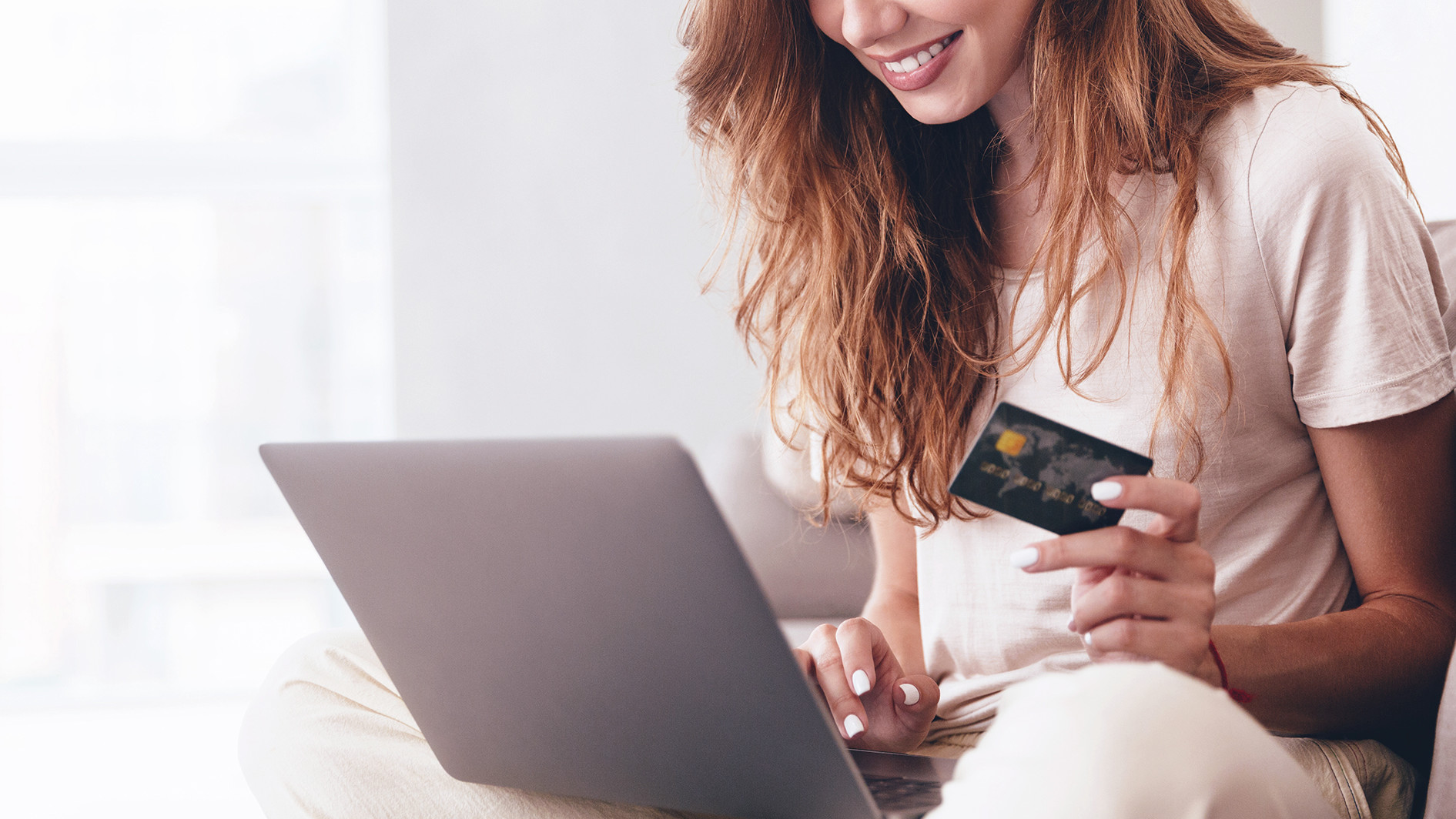 Femme procédant à un achat en ligne avec sa carte de crédit en main