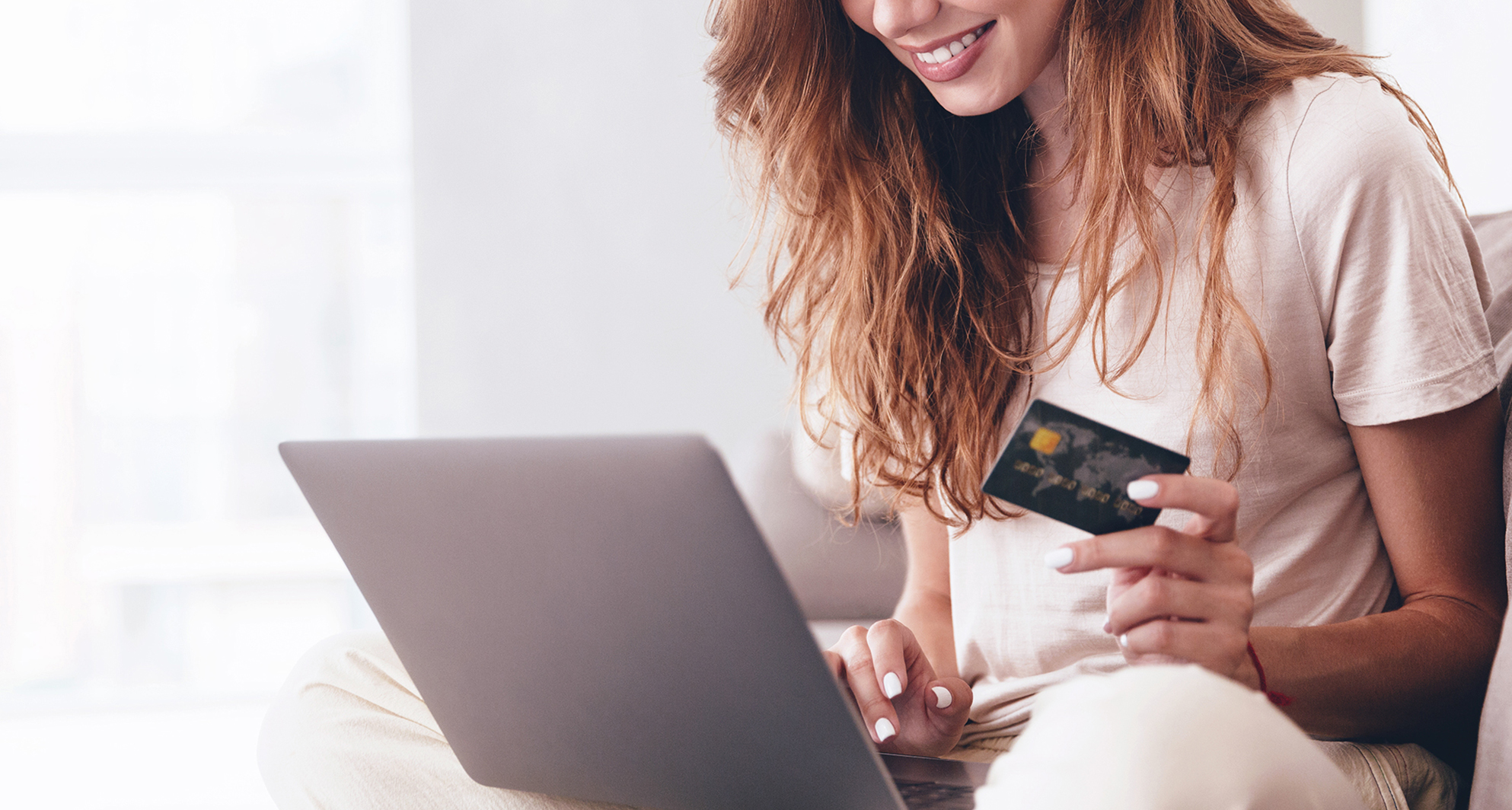 Femme procédant à un achat en ligne avec sa carte de crédit en main